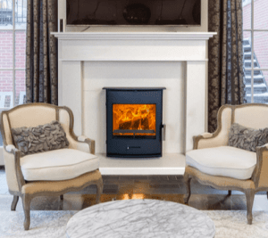 A wood burning stove with two luxury chairs in front of it. 