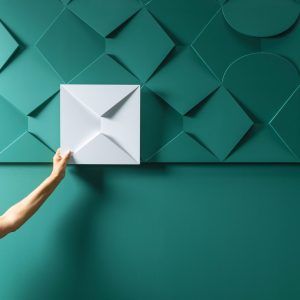 A 3D wall panel in the shape of an envelope, ready to be placed on a stunning teal wall adorned with a captivating geometric pattern.