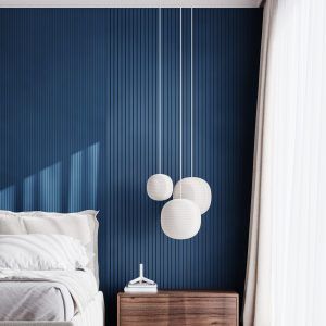 A contemporary bedroom featuring a deep blue 3D wall panel with vertical grooves, a white bed with crisp linens, and a sleek wooden nightstand.